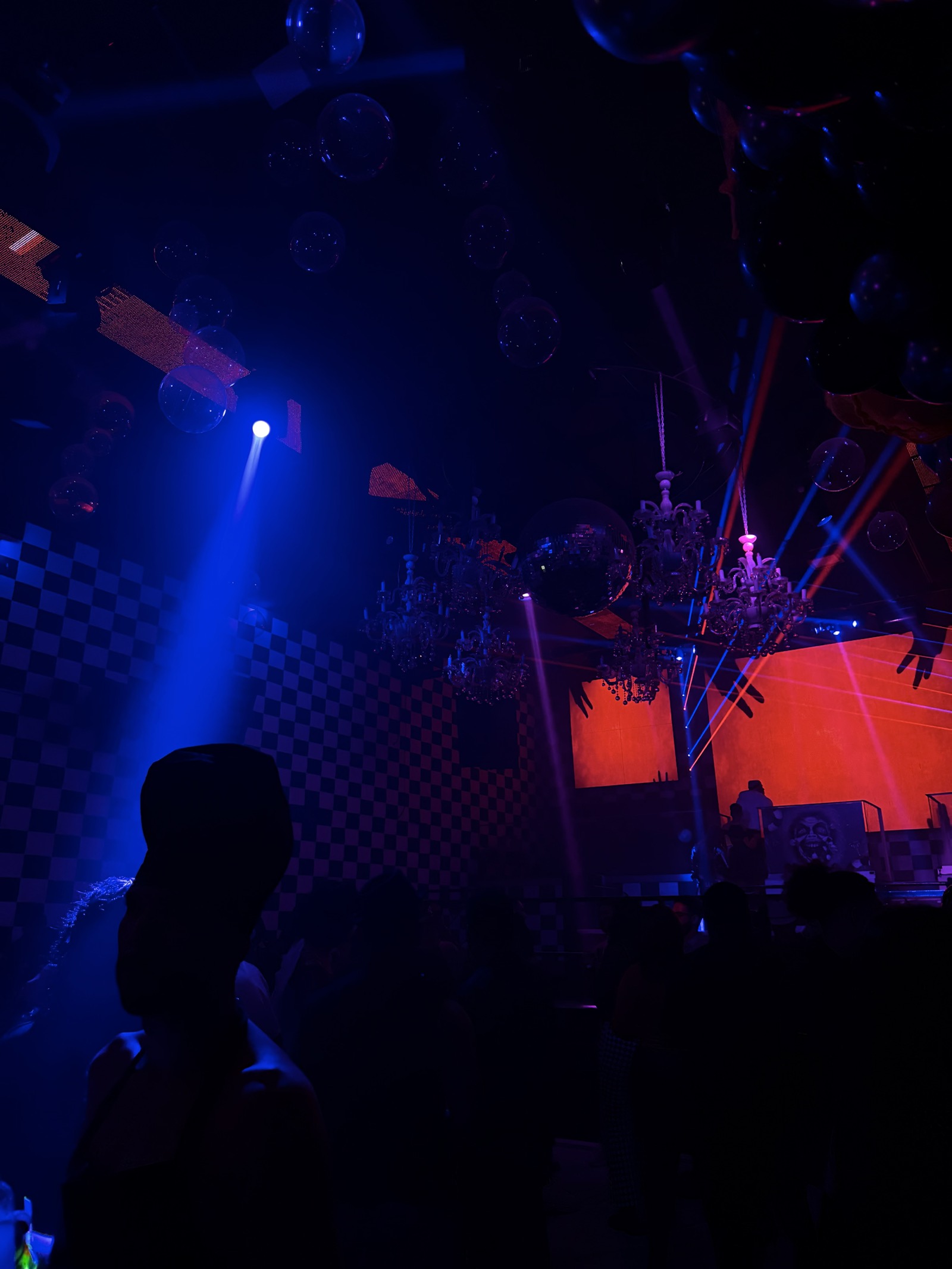 Escenario de un concierto iluminado en azul y rojo, con siluetas del público.